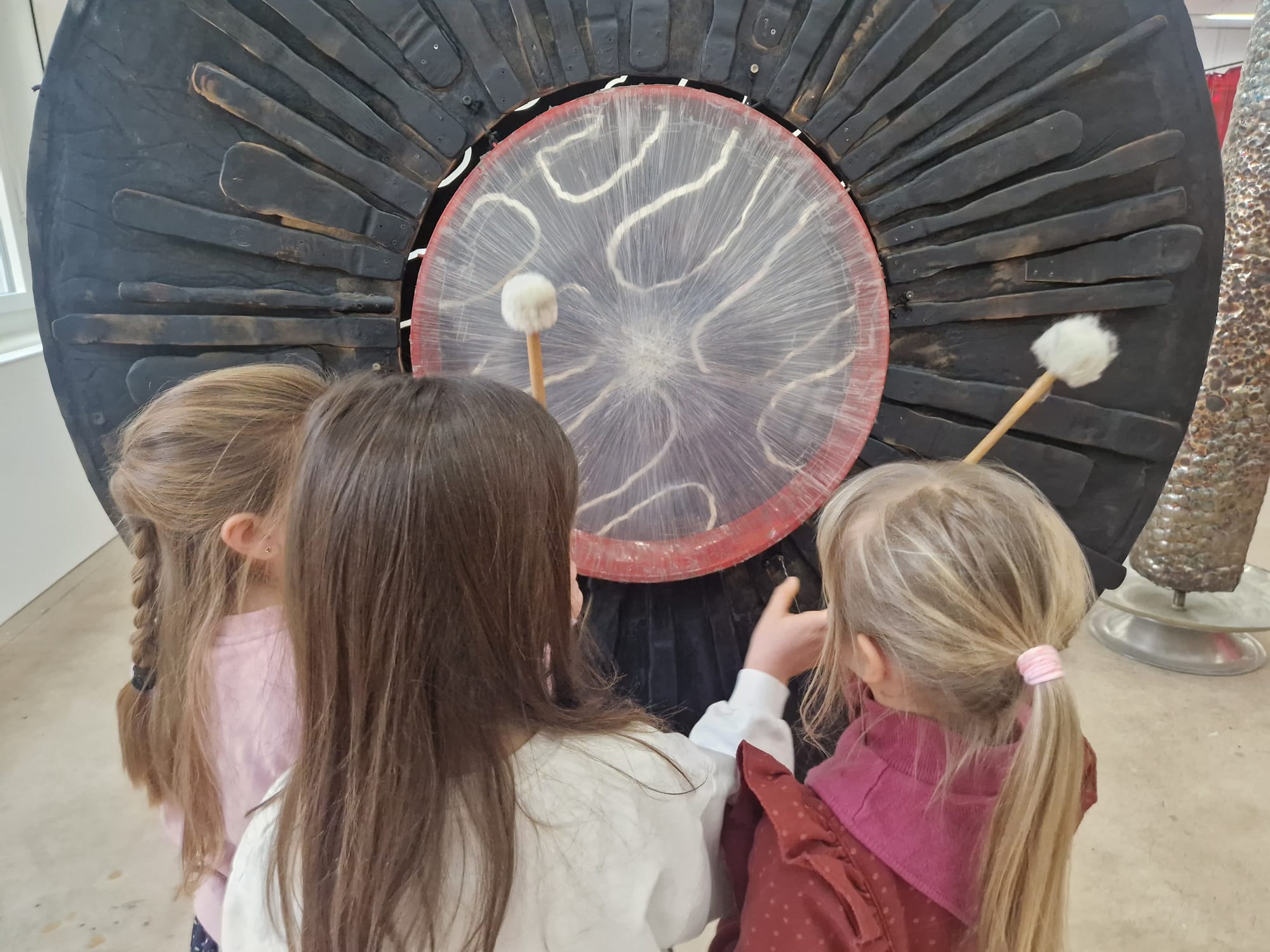Kinder spielen die grosse Klangscheibe mit Schlägeln